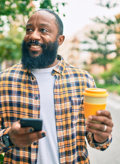 Man with yellow plaid shirt, yellow coffee cup, smartphone.